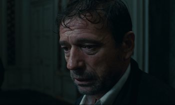 Movie still from “The Confession” (1970), directed by Costa-Gavras – A person wearing a suit and tie; Close Up shot, Low angle