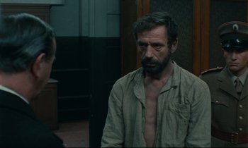 Movie still from “The Confession” (1970), directed by Costa-Gavras – A man in a tan shirt is talking to another man in a tan shirt; Medium shot, Over the shoulder angle