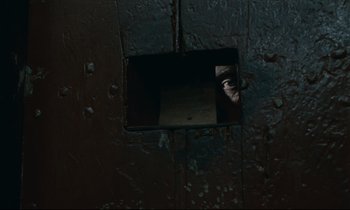 Movie still from “The Confession” (1970), directed by Costa-Gavras – A man is looking through a hole in the wall; Extreme Close Up shot, High angle