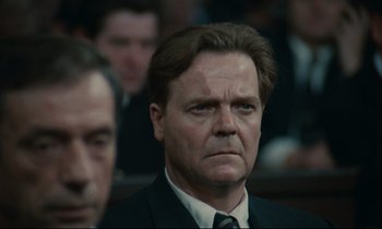 Movie still from “The Confession” (1970), directed by Costa-Gavras – A person wearing a suit and tie; Close Up shot, Low angle