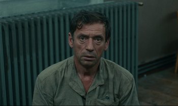 Movie still from “The Confession” (1970), directed by Costa-Gavras – A person wearing a green shirt; Close Up shot, High angle