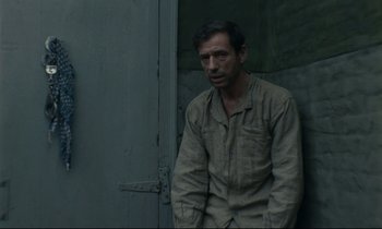 Movie still from “The Confession” (1970), directed by Costa-Gavras – A man standing in front of a door; Medium shot, High angle