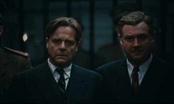 Movie still from “The Confession” (1970), directed by Costa-Gavras – Two men in suits and ties standing next to each other; Close Up shot, Low angle