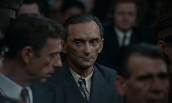 Movie still from “The Confession” (1970), directed by Costa-Gavras – An older man in a suit and tie looking into the camera; Close Up shot, High angle