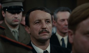 Movie still from “The Confession” (1970), directed by Costa-Gavras – A person wearing a suit and tie; Close Up shot, Over the shoulder angle