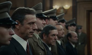 Movie still from “The Confession” (1970), directed by Costa-Gavras – A group of men standing next to each other in uniform; Medium shot, Low angle
