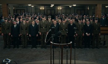 Movie still from “The Confession” (1970), directed by Costa-Gavras – A group of men standing in front of a microphone; Wide shot, High angle