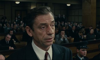 Movie still from “The Confession” (1970), directed by Costa-Gavras – A person wearing a suit and tie; Close Up shot, Low angle
