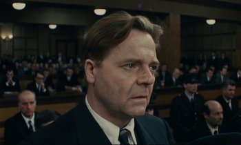 Movie still from “The Confession” (1970), directed by Costa-Gavras – A person wearing a suit and tie; Close Up shot, Low angle