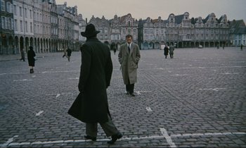 Movie still from “The Confession” (1970), directed by Costa-Gavras – Two men are walking on a cobblestone street; Wide shot, High angle