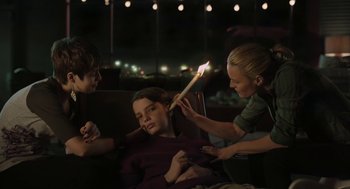 Movie still from “The Congress” (2013), directed by Ari Folman – A group of young people lighting candles on a man; Medium shot, Over the shoulder angle