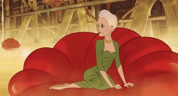 Movie still from “The Congress” (2013), directed by Ari Folman – A woman sitting on top of a red couch; Medium shot, Over the shoulder angle