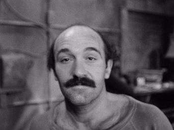 Movie still from “The Connection” (1961), directed by Shirley Clarke – Black and white photograph of a man with a mustache; Close Up shot, High angle
