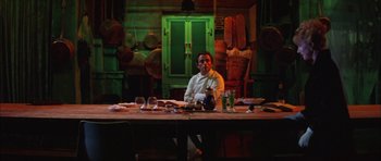 Movie still from “The Cook, the Thief, His Wife & Her Lover” (1989), directed by Peter Greenaway – A man sitting at a dinner table in front of a bunch of plates; Wide shot, Low angle