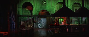 Movie still from “The Cook, the Thief, His Wife & Her Lover” (1989), directed by Peter Greenaway – A stage set with a clock and people sitting around it; Extreme Wide shot, Low angle