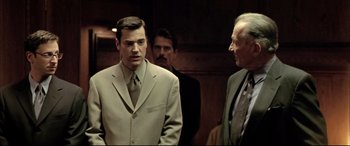 Movie still from “The Cooler” (2003), directed by Wayne Kramer – A man in a suit and tie standing next to two other men; Medium shot, Over the shoulder angle