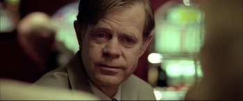 Movie still from “The Cooler” (2003), directed by Wayne Kramer – An older man wearing a suit and tie looking at the camera; Close Up shot, Over the shoulder angle