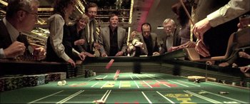 Movie still from “The Cooler” (2003), directed by Wayne Kramer – A group of men standing next to a table; Wide shot, High angle