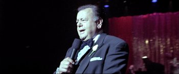 Movie still from “The Cooler” (2003), directed by Wayne Kramer – A person holding a microphone on a stage; Close Up shot, Low angle