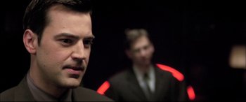 Movie still from “The Cooler” (2003), directed by Wayne Kramer – A man in a suit and tie standing next to another man in a suit and tie; Close Up shot, Over the shoulder angle