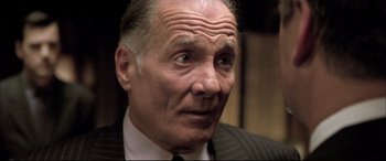 Movie still from “The Cooler” (2003), directed by Wayne Kramer – An older man wearing a suit and tie looking at the camera; Close Up shot, Low angle
