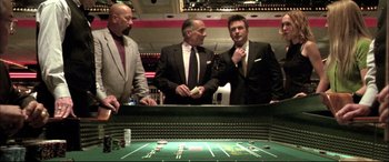 Movie still from “The Cooler” (2003), directed by Wayne Kramer – A group of men in suits standing around a table; Medium shot, High angle