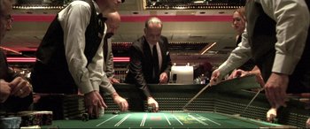 Movie still from “The Cooler” (2003), directed by Wayne Kramer – A group of men standing around a green table; Medium shot, Low angle