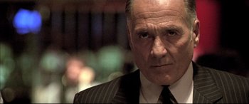Movie still from “The Cooler” (2003), directed by Wayne Kramer – An older man wearing a suit and tie looking at the camera; Close Up shot, Low angle