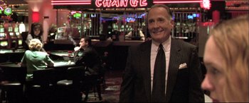 Movie still from “The Cooler” (2003), directed by Wayne Kramer – A man in a suit standing in front of a table; Medium shot, Over the shoulder angle