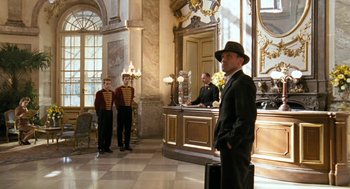 Movie still from “The Counterfeiters” (2007), directed by Stefan Ruzowitzky – A group of men standing around a hotel lobby; Wide shot, Low angle