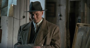 Movie still from “The Counterfeiters” (2007), directed by Stefan Ruzowitzky – A man wearing a hat and a coat; Close Up shot, Over the shoulder angle
