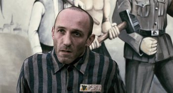 Movie still from “The Counterfeiters” (2007), directed by Stefan Ruzowitzky – A man in a striped shirt with a hammer in front of a painting; Medium shot, Over the shoulder angle