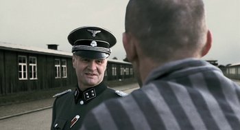Movie still from “The Counterfeiters” (2007), directed by Stefan Ruzowitzky – A man in a uniform talking to another man; Medium shot, Over the shoulder angle
