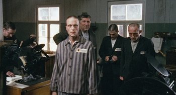 Movie still from “The Counterfeiters” (2007), directed by Stefan Ruzowitzky – A group of men standing in a room; Medium shot, Over the shoulder angle