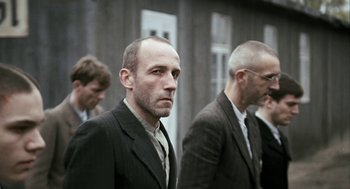 Movie still from “The Counterfeiters” (2007), directed by Stefan Ruzowitzky – A group of men standing next to each other in suits; Medium shot, Over the shoulder angle