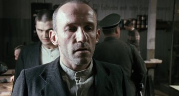 Movie still from “The Counterfeiters” (2007), directed by Stefan Ruzowitzky – A person wearing a suit and tie; Close Up shot, Over the shoulder angle