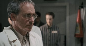 Movie still from “The Counterfeiters” (2007), directed by Stefan Ruzowitzky – A man in a lab coat and glasses looking down; Close Up shot, Over the shoulder angle