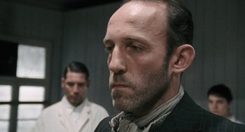 Movie still from “The Counterfeiters” (2007), directed by Stefan Ruzowitzky – A man in a suit and tie next to another man in a suit and tie; Close Up shot, Low angle