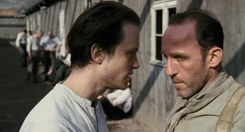 Movie still from “The Counterfeiters” (2007), directed by Stefan Ruzowitzky – Two men standing next to each other in front of a building; Close Up shot, Over the shoulder angle