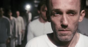 Movie still from “The Counterfeiters” (2007), directed by Stefan Ruzowitzky – A person wearing a white t - shirt; Close Up shot, Over the shoulder angle