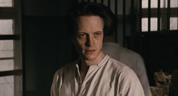 Movie still from “The Counterfeiters” (2007), directed by Stefan Ruzowitzky – A man in a white shirt is looking at the camera; Close Up shot, Low angle