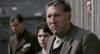 Movie still from “The Counterfeiters” (2007), directed by Stefan Ruzowitzky – A man and a boy are standing next to each other; Close Up shot, Low angle