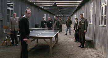 Movie still from “The Counterfeiters” (2007), directed by Stefan Ruzowitzky – A group of men standing around a ping - pong table; Wide shot, Over the shoulder angle