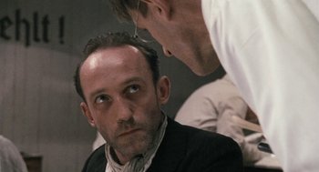 Movie still from “The Counterfeiters” (2007), directed by Stefan Ruzowitzky – A man in a suit and tie looking at another man in a white shirt; Close Up shot, Over the shoulder angle