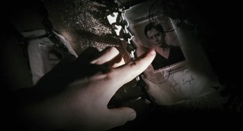 Movie still from “The Counterfeiters” (2007), directed by Stefan Ruzowitzky – A person's hand is holding a chain next to a picture of a woman; Extreme Close Up shot, Overhead angle