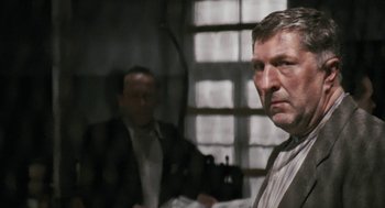 Movie still from “The Counterfeiters” (2007), directed by Stefan Ruzowitzky – A man in a suit and tie standing next to another man in a suit and tie; Close Up shot, Over the shoulder angle