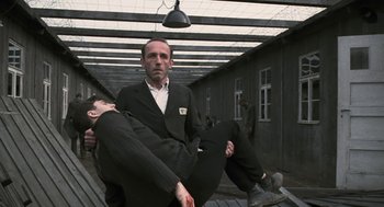 Movie still from “The Counterfeiters” (2007), directed by Stefan Ruzowitzky – A man in a suit and tie holding another man in a suit and tie; Wide shot, Low angle