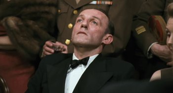 Movie still from “The Counterfeiters” (2007), directed by Stefan Ruzowitzky – A man in a suit and bow tie is looking up; Close Up shot, Low angle