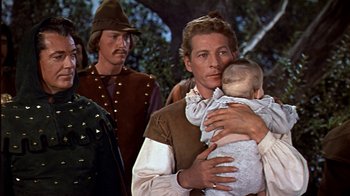 Movie still from “The Court Jester” (1955), directed by Melvin Frank – A man holding a baby in his arms while standing next to another man; Medium shot, High angle