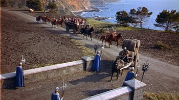 Movie still from “The Court Jester” (1955), directed by Melvin Frank – A group of people riding on a horse drawn carriage down a road; Extreme Wide shot, High angle